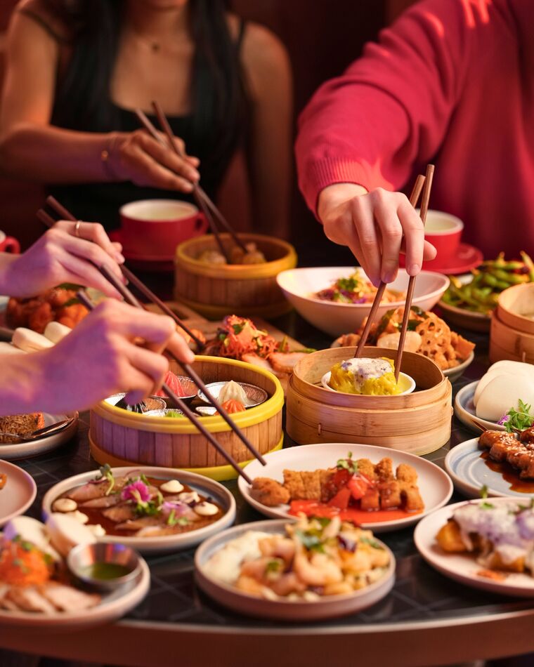 Hands reaching across a full shared table
